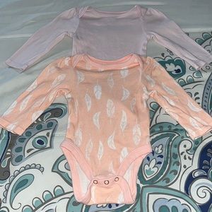 2 onesies, one is a plain light pink the other is pink with white feathers.
